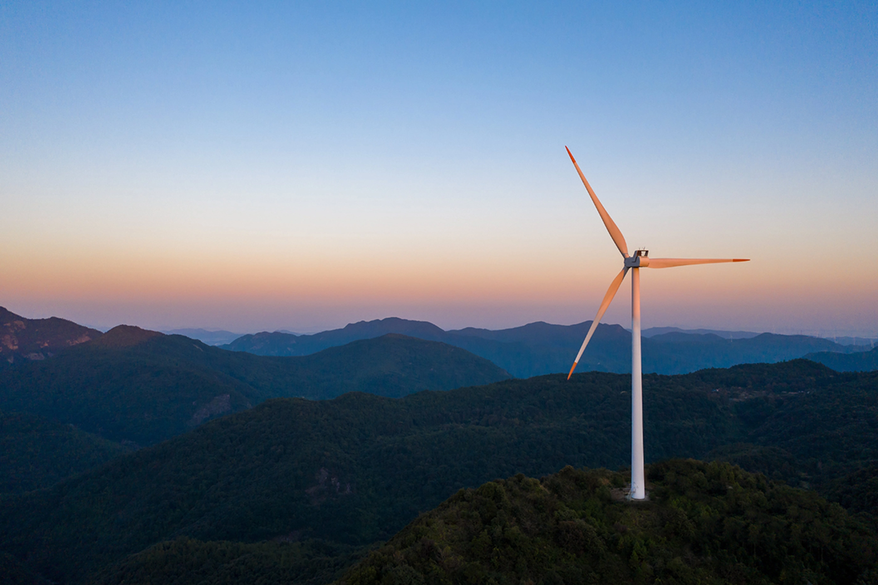 Morning drone shot of mountain top industrial wind power plant.