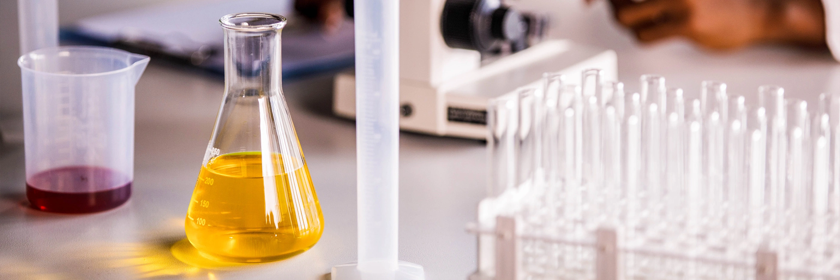 Laboratory equipment on a desk with a scientist in the background.