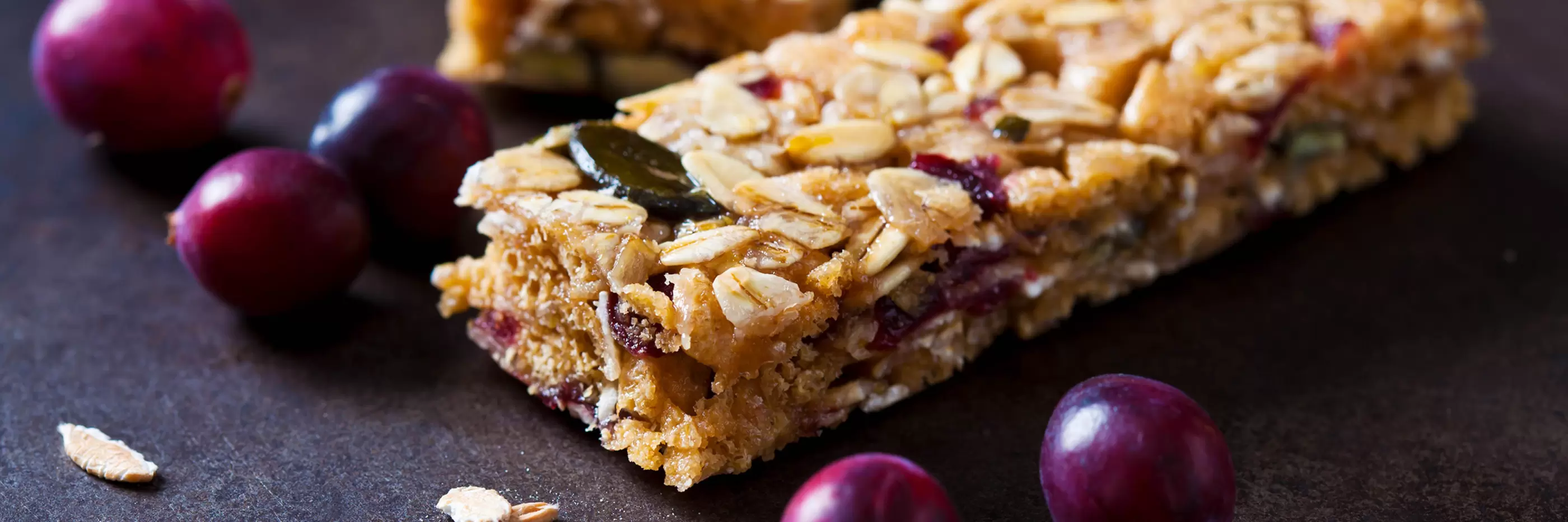 Muesli bars with cranberries and oat flakes on dark background.