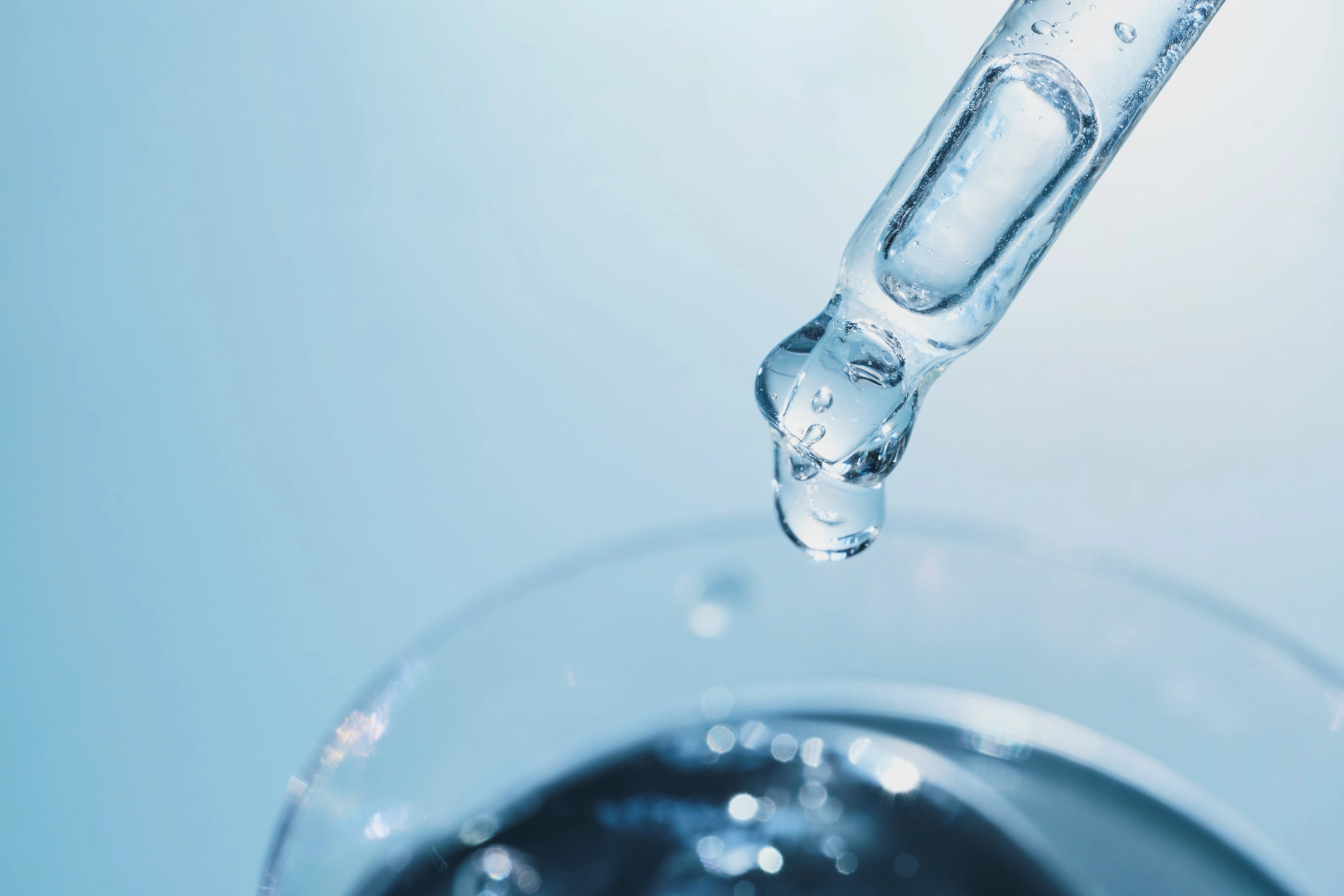 298654509 - pipette dropping clear liquid beauty serum or medical solution into glass container