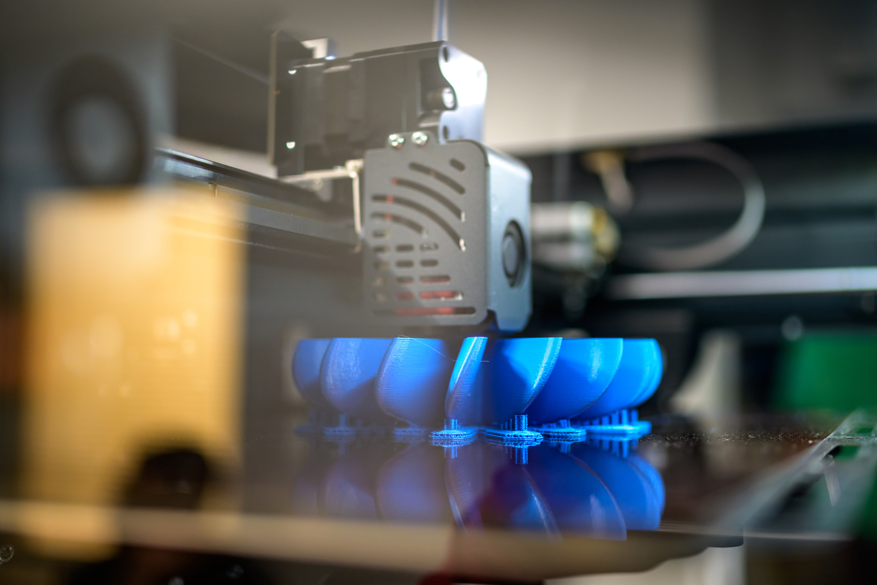 Close-up view of 3D printing complicated plastic part from blue filament. Producing of 3D object from digital model using additive manufacturing.