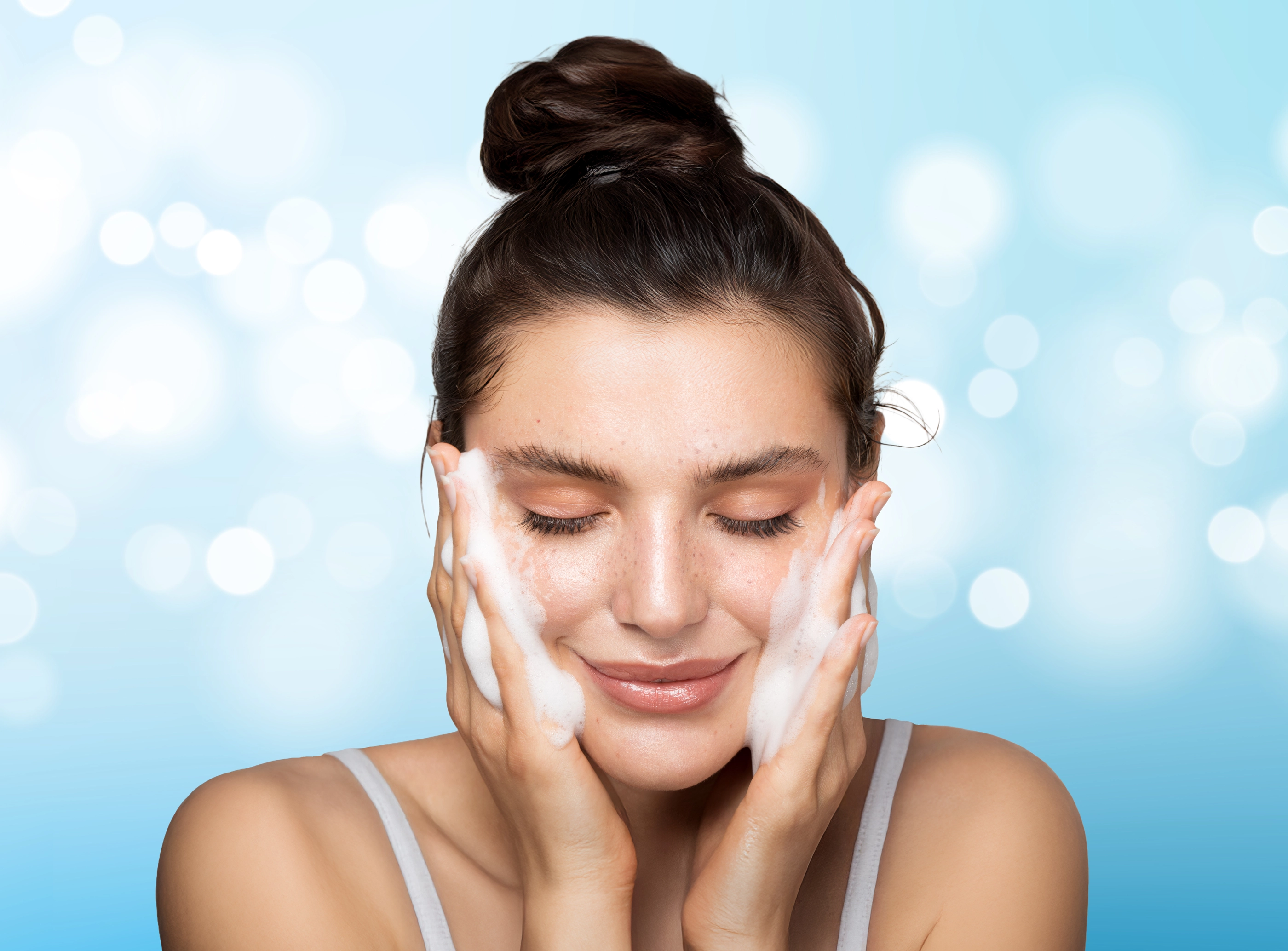 Close up studio shot of a beautiful woman with perfect skin, while she cleaning her face