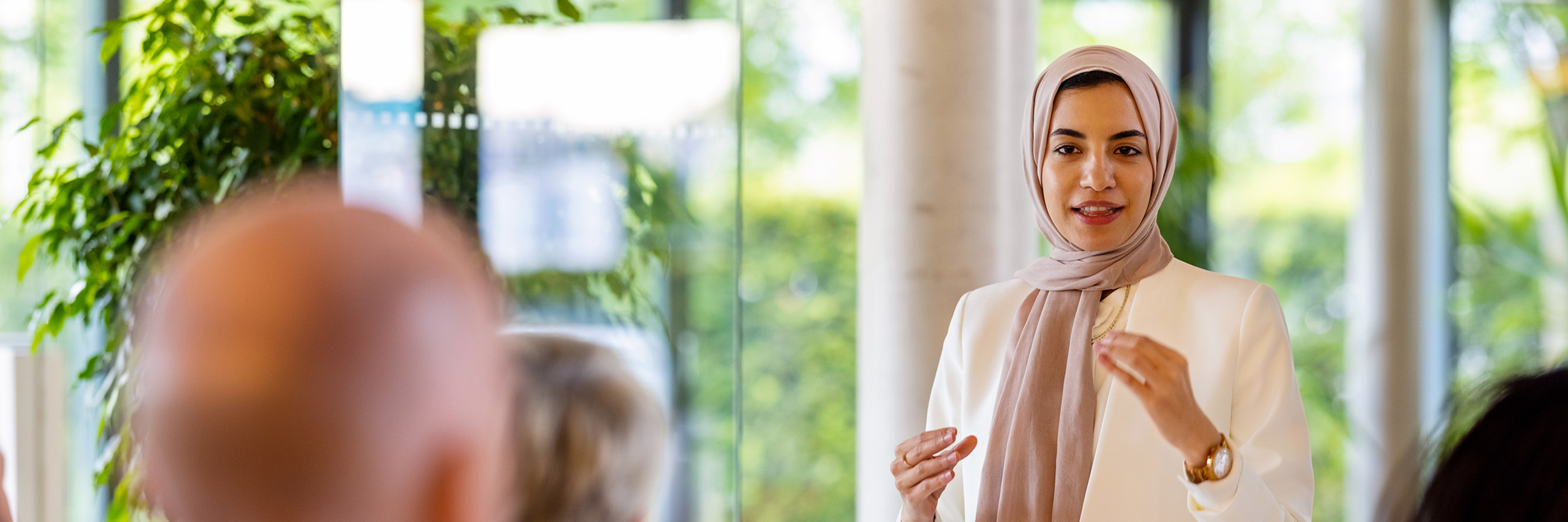 Young middle eastern businesswoman giving a speech in a business seminar. Muslim woman wearing headscarf addressing the audience in a business conference.