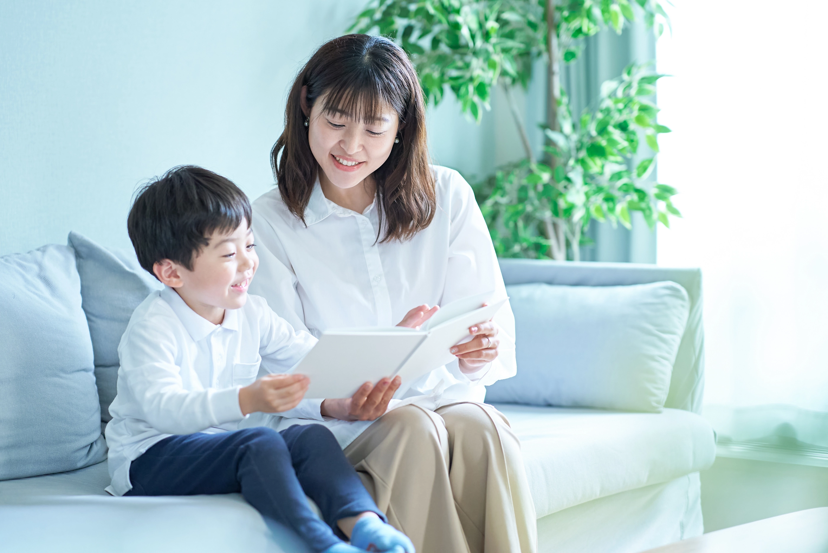 mother and boy sitting on the sofa and reading picture book