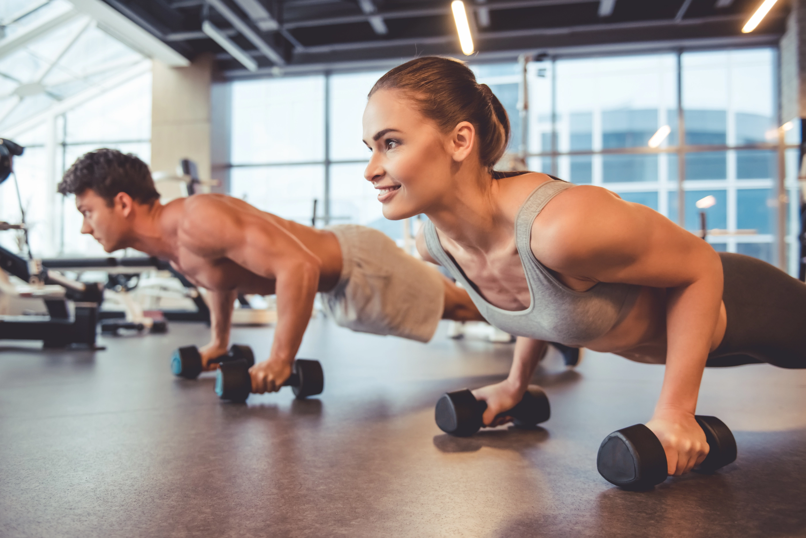 Attractive young sports people are working out with dumbbells and doing push ups in gym; Shutterstock ID 561748330; purchase_order: nfi; job: nfi; client: ; other: 