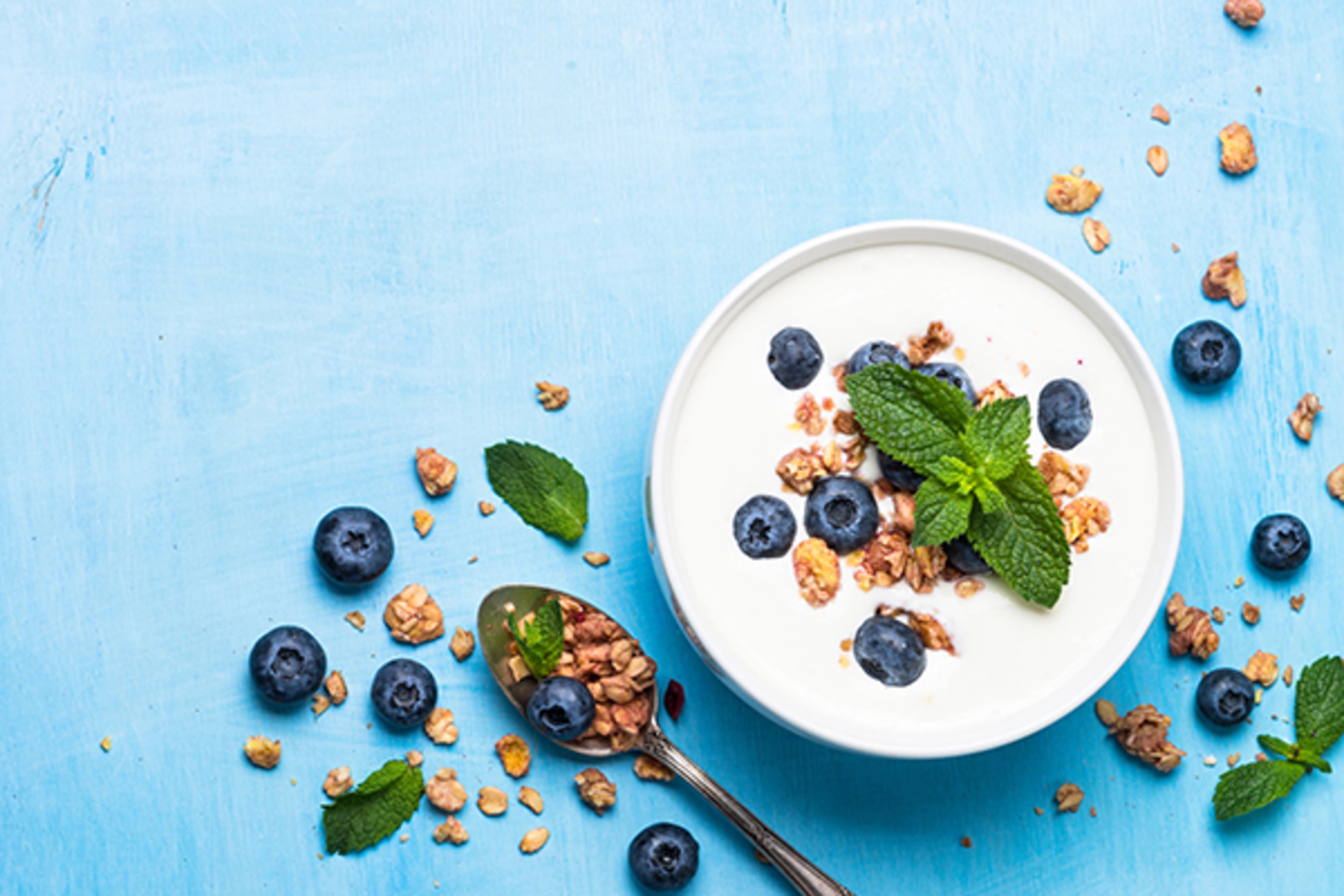Greek yogurt granola and blueberries on blue table. Top view copy space. Healthy food, snack or breakfast.