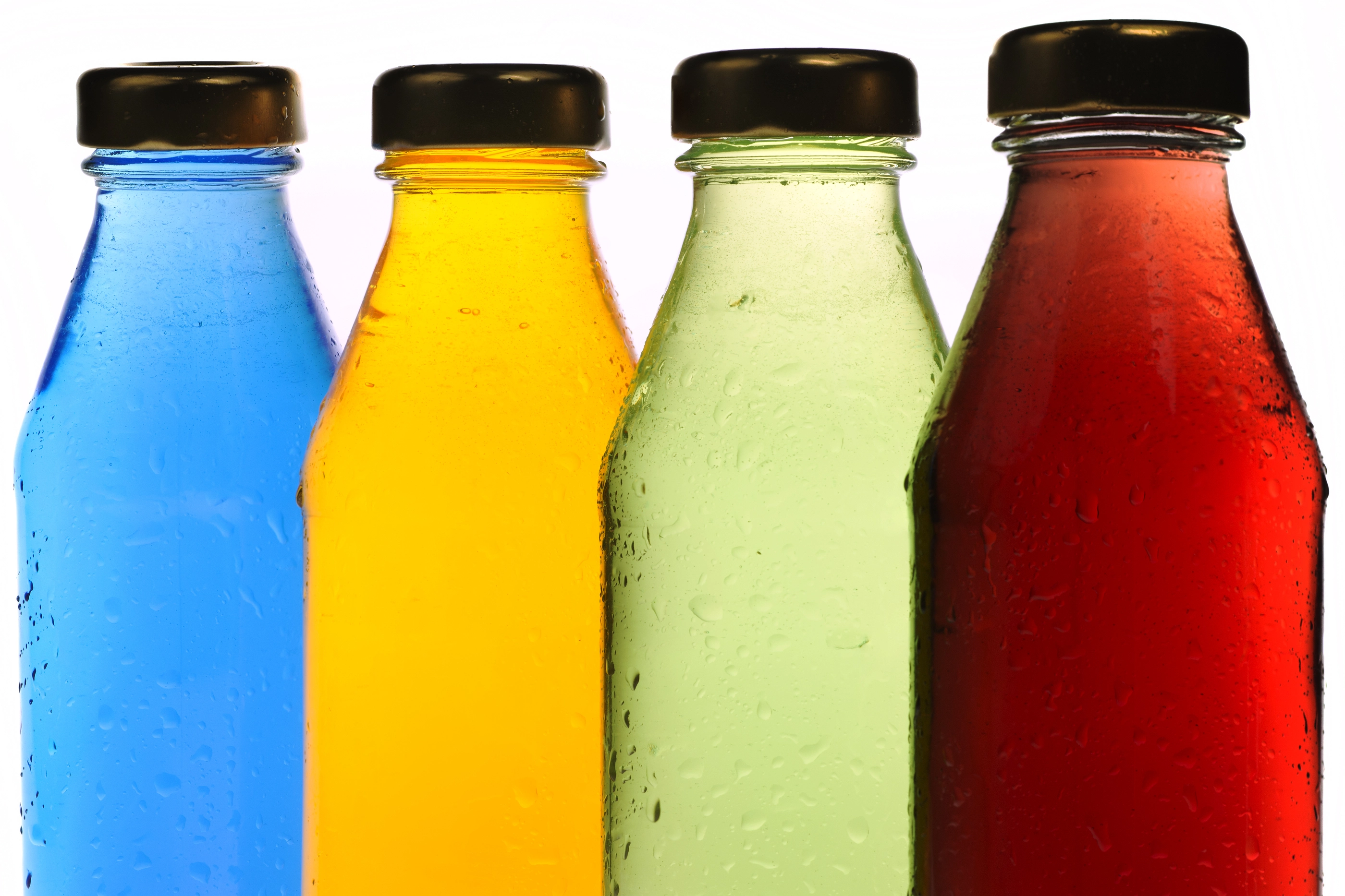 Close-Up Of Multi Colored Drink Bottles Against White Background