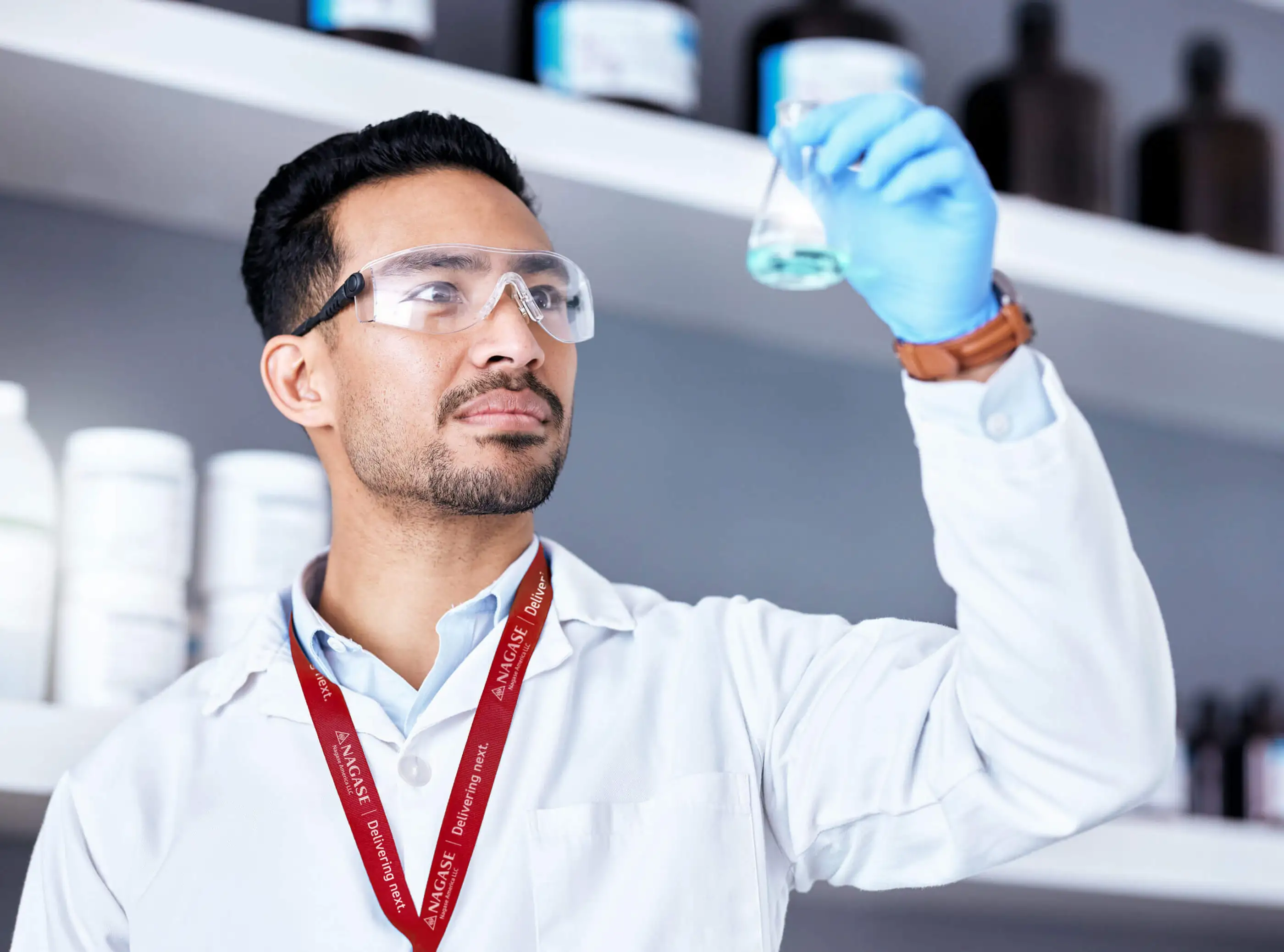 Chemist wearing Nagase lanyard inspecting chemical beaker