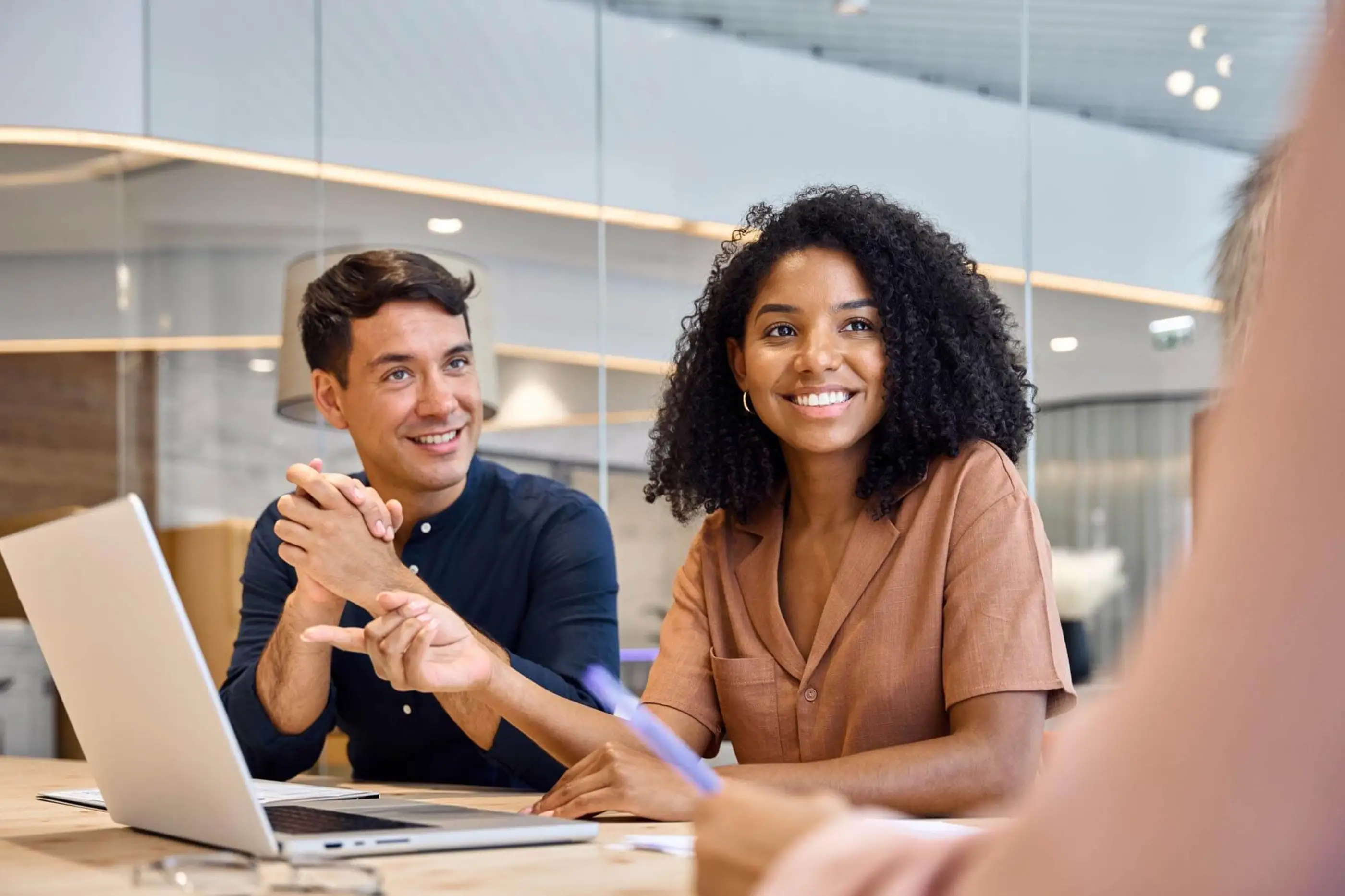Three people in front of a computer in a meeting 