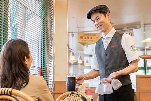 Saizeriya employee speaking to a customer holding Tritan wine glasses