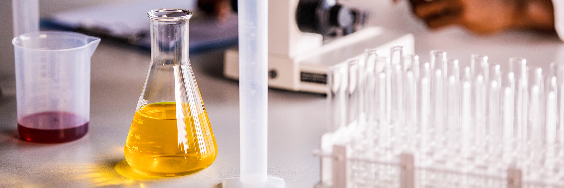 Focus Areas Laboratory equipment on a desk with a scientist in the background.