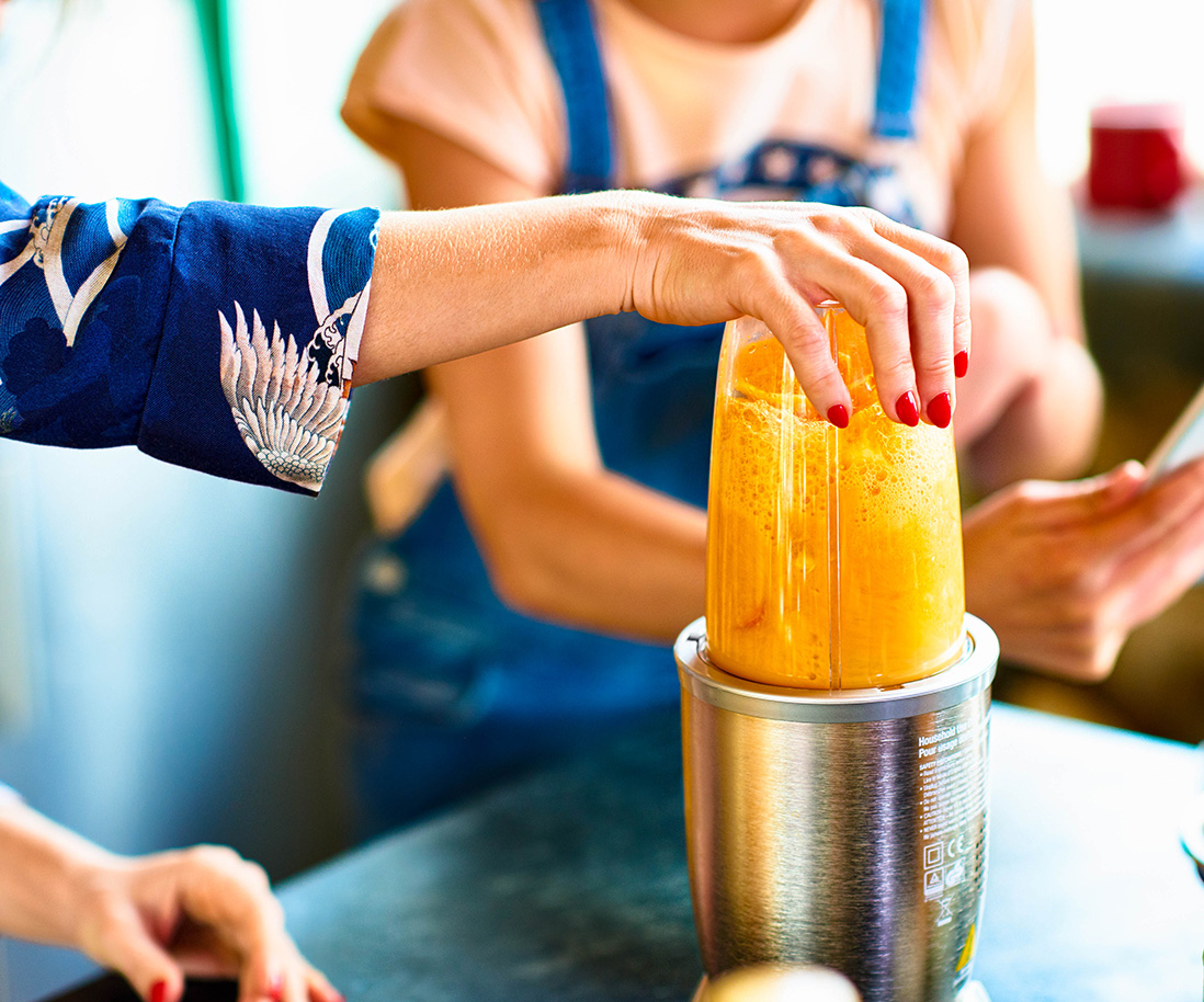 50-50 Woman preparing smoothie in blender.
